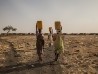 Tres mujeres llevando agua en un campo de desplazados en Melut, Sudán del Sur. || Anna Surinyach